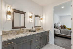 Ensuite bathroom featuring double vanity, light colored carpet, and recessed lighting