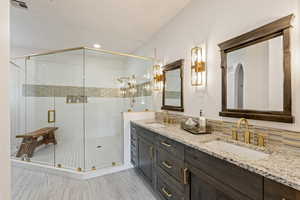 Full bath with double vanity and a shower stall