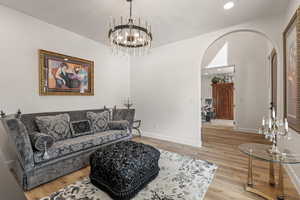 Living room with light wood-style flooring, a chandelier, and arched walkways