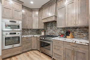Kitchen featuring stainless steel appliances, light stone countertops, decorative backsplash, light wood-style flooring, and recessed lighting