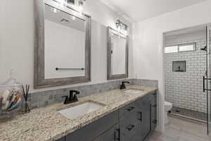 Bathroom featuring double vanity, a stall shower, and backsplash