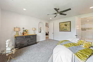 Carpeted bedroom featuring arched walkways and ceiling fan
