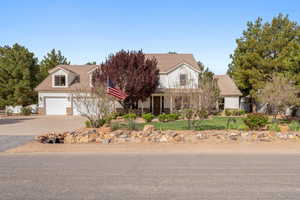 View of front of property with stone siding, covered porch, driveway, a garage, and a front yard