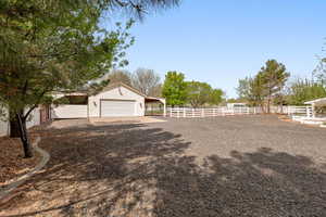 View of yard with driveway, a carport, an attached garage, and an outdoor structure