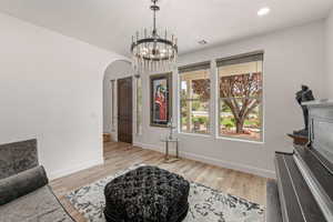 Sitting room featuring arched walkways, light wood finished floors, and suspended lighting