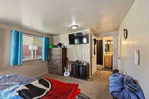 Carpeted bedroom with ensuite bathroom and baseboards