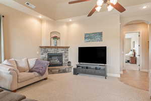 Living area with light colored carpet, ceiling fan, a fireplace, recessed lighting, and arched walkways