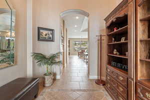 Corridor featuring arched walkways, inlaid floor details, light tile patterned floors, and recessed lighting