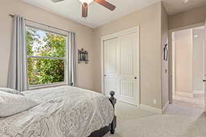 Bedroom featuring light colored carpet, a closet, and a ceiling fan