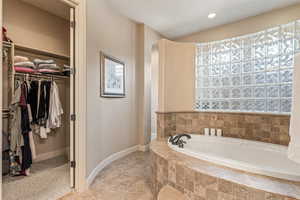 Bathroom featuring a walk in closet, a garden tub, light tile patterned floors, and recessed lighting
