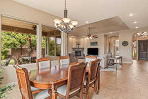Dining room featuring ceiling fan, hanging lights, a stone fireplace, and arched walkways