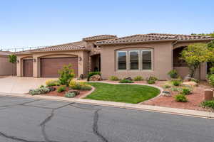 Mediterranean / spanish-style house with stucco siding, an attached garage, concrete driveway, a tiled roof, and a front lawn