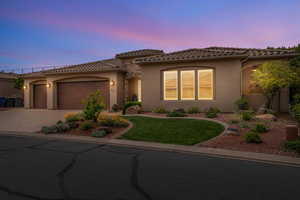 Mediterranean / spanish-style home with stucco siding, an attached garage, driveway, a tile roof, and a yard