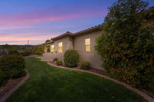 Property exterior at dusk with a yard and stucco siding