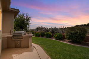 Yard at dusk featuring a patio area, area for grilling, and a fenced backyard