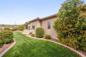 View of side of home featuring a lawn and stucco siding