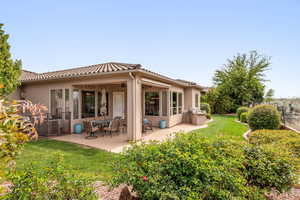Rear view of house featuring stucco siding, a yard, a patio area, and a tile roof