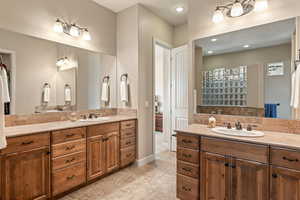 Full bathroom featuring two vanities, recessed lighting, light tile patterned flooring, a walk in shower, and backsplash