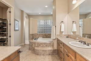 Full bath with vanity, a bath, and a spacious closet