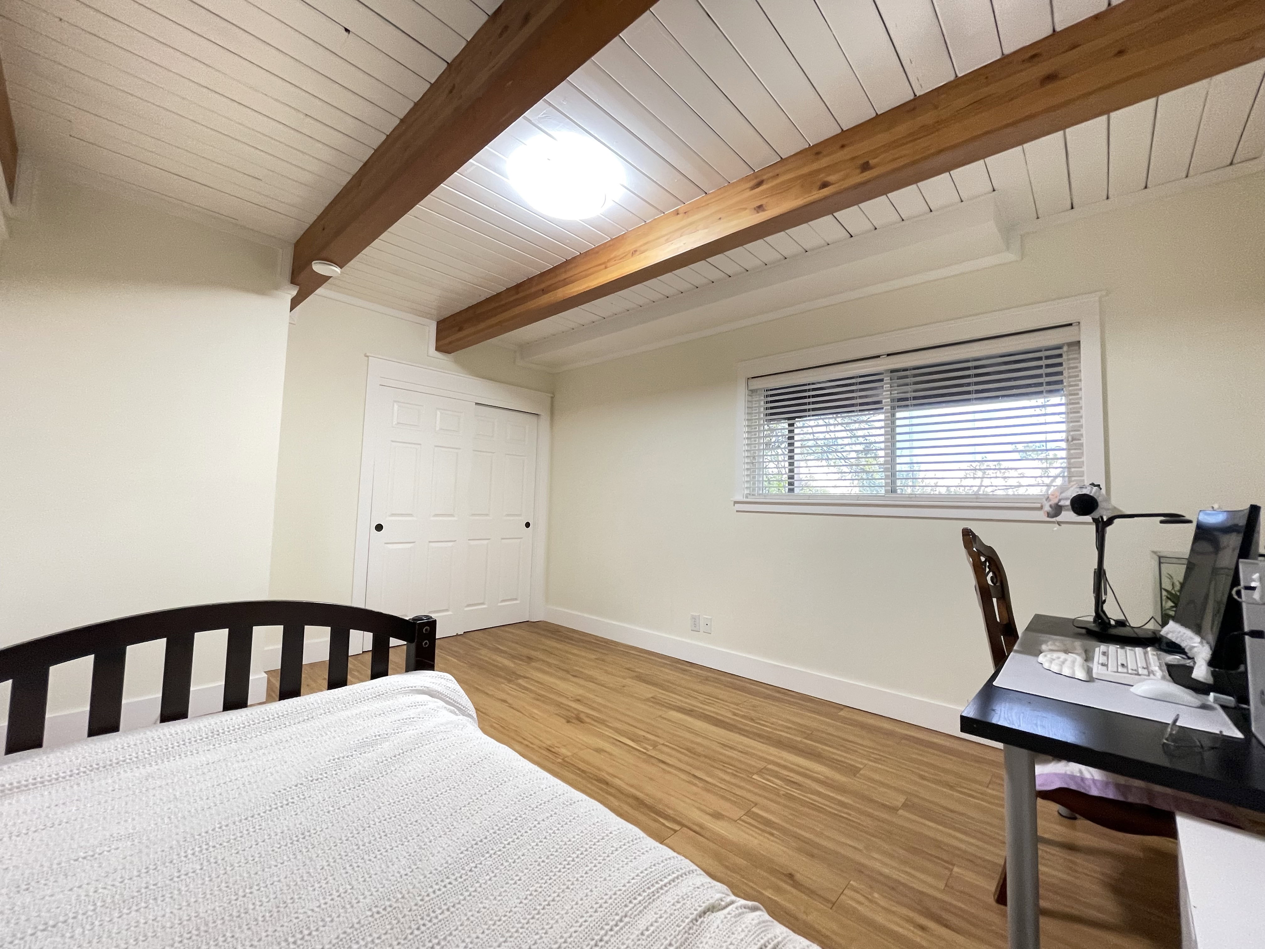 Bedroom with light wood-style flooring and a wood ceiling with exposed beams