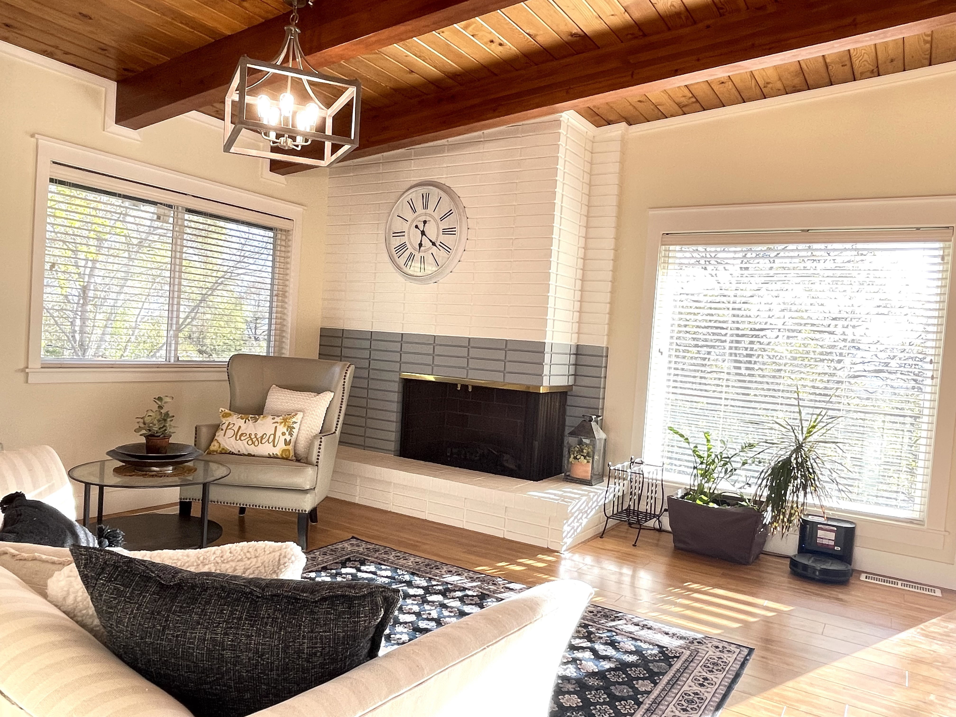 Living area with a wooden ceiling with exposed beams, wood finished floors, a fireplace, and healthy amount of natural light