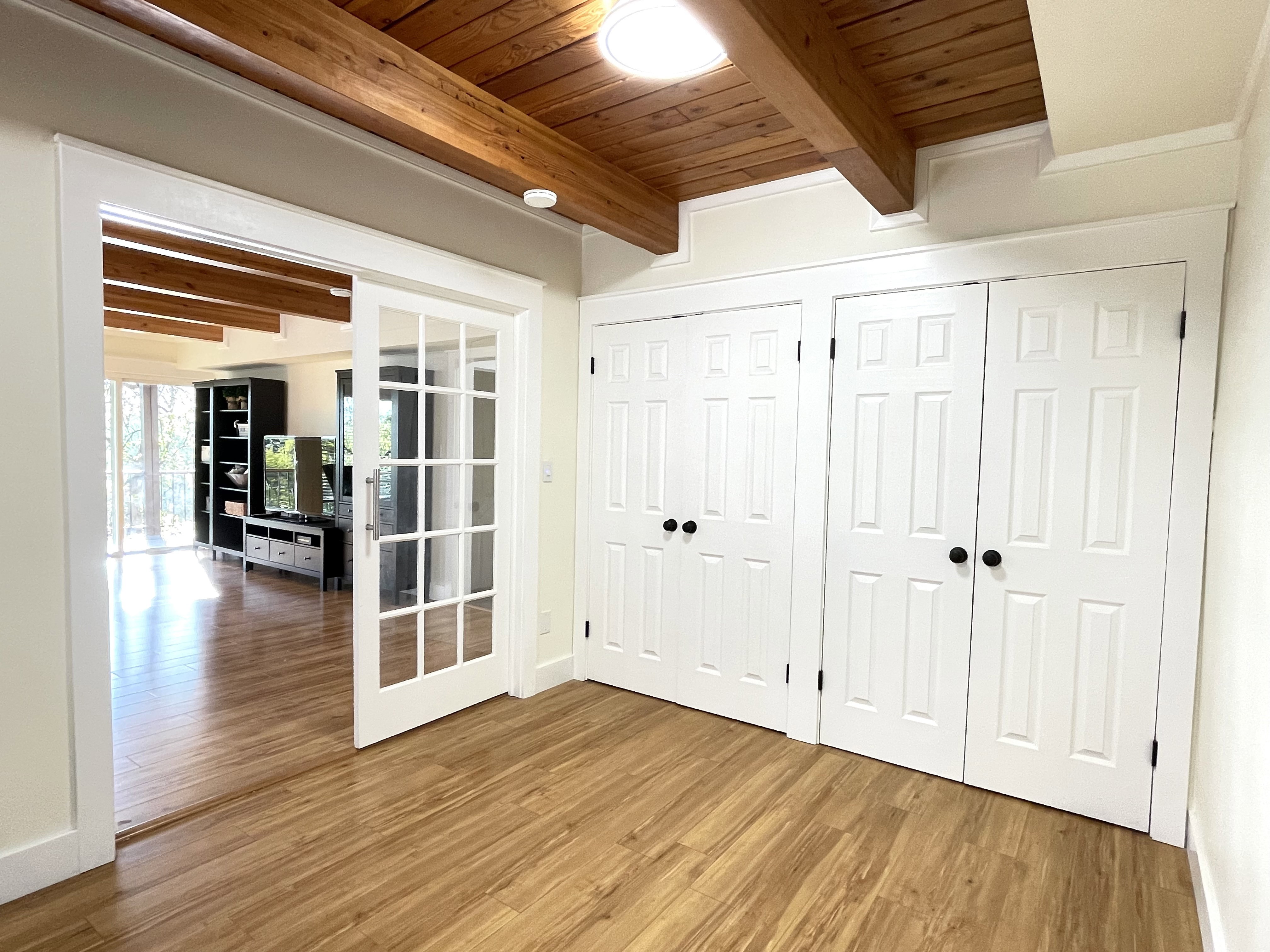 Interior space featuring french doors, light wood-style floors, and a wooden ceiling with exposed beams