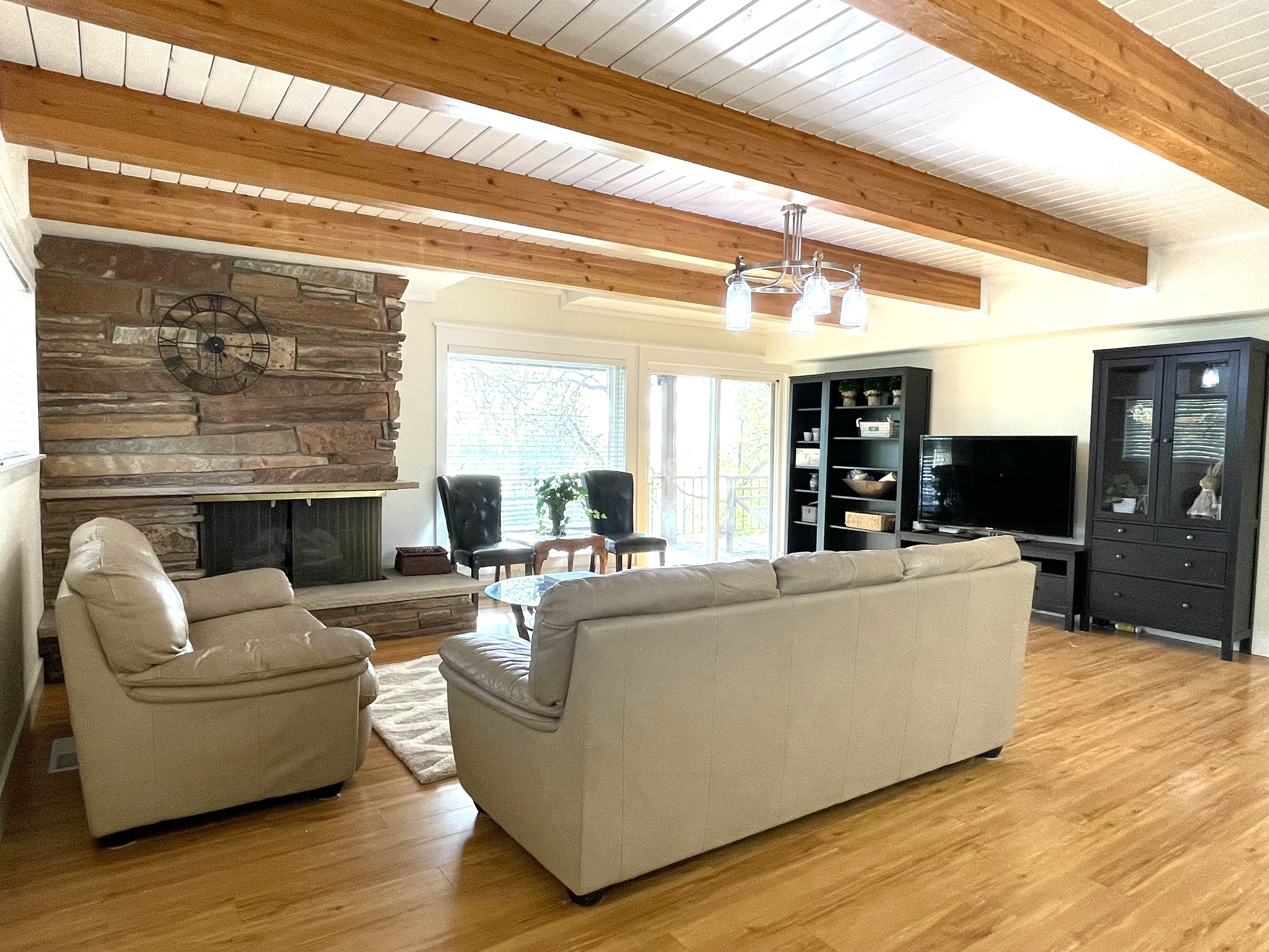Living room featuring a fireplace, light wood finished floors, and beam ceiling