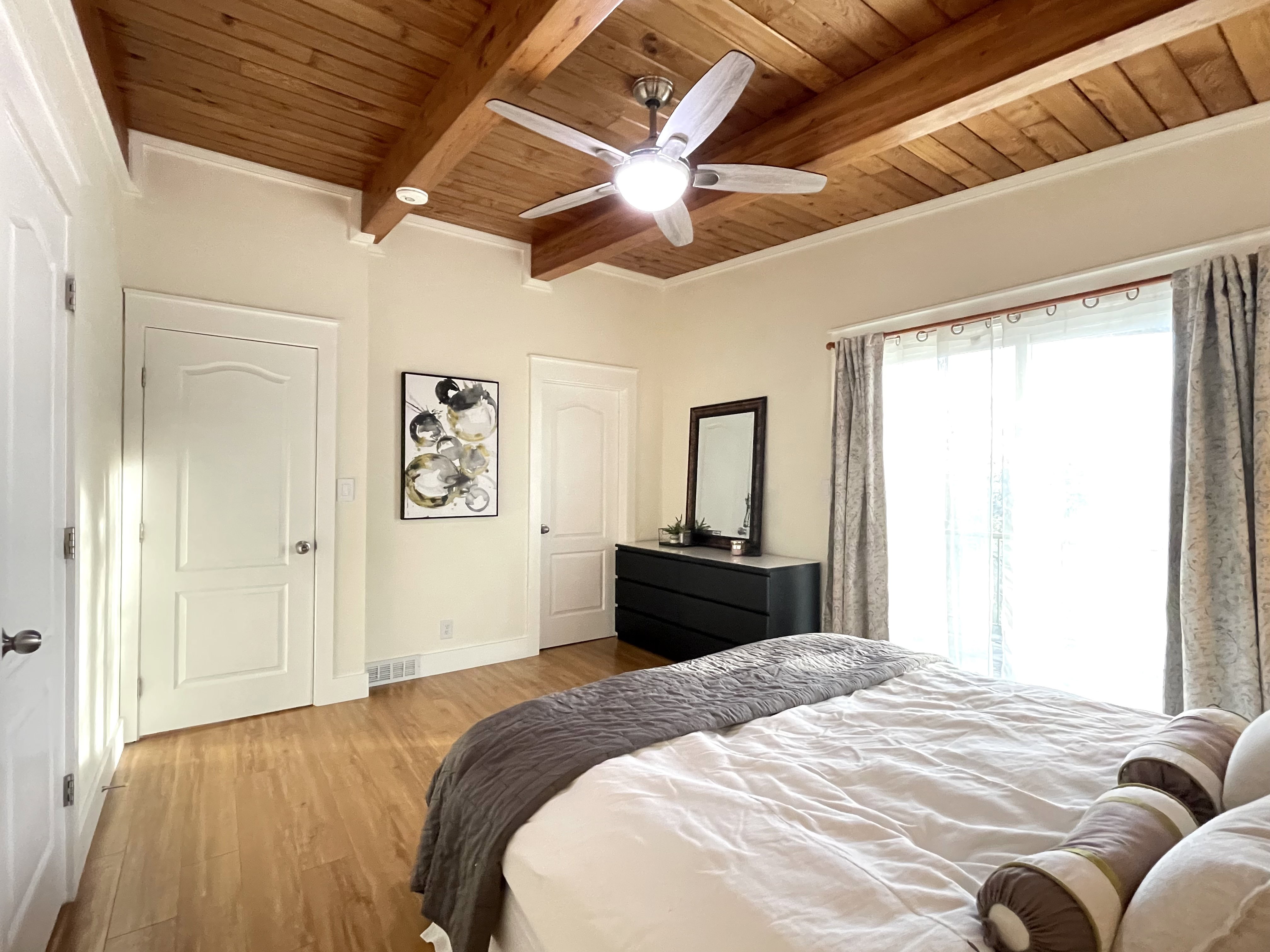Bedroom featuring light wood finished floors, a wood ceiling with exposed beams, and a ceiling fan