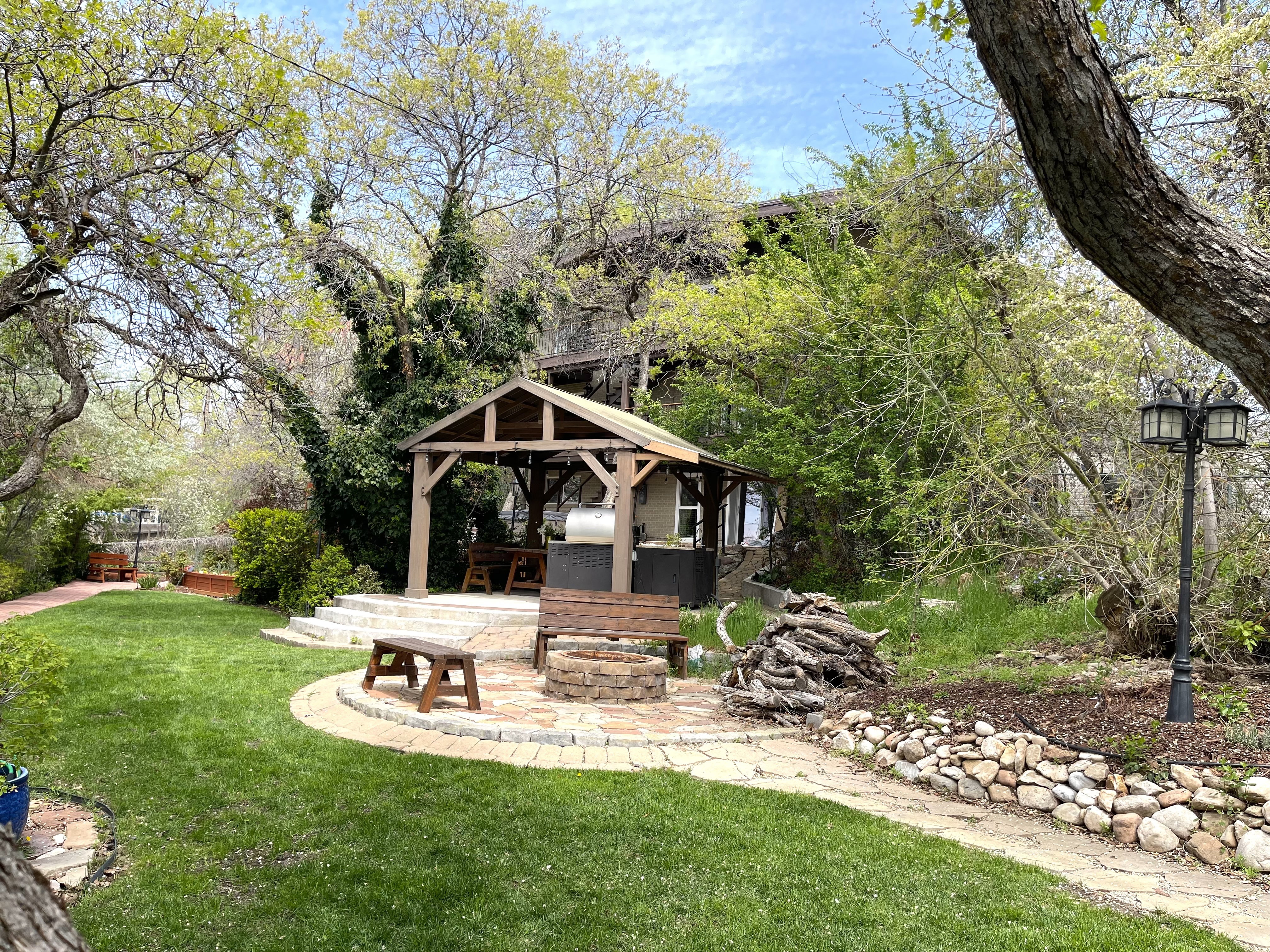 View of grassy yard featuring a patio, view of scattered trees, and an outdoor fire pit
