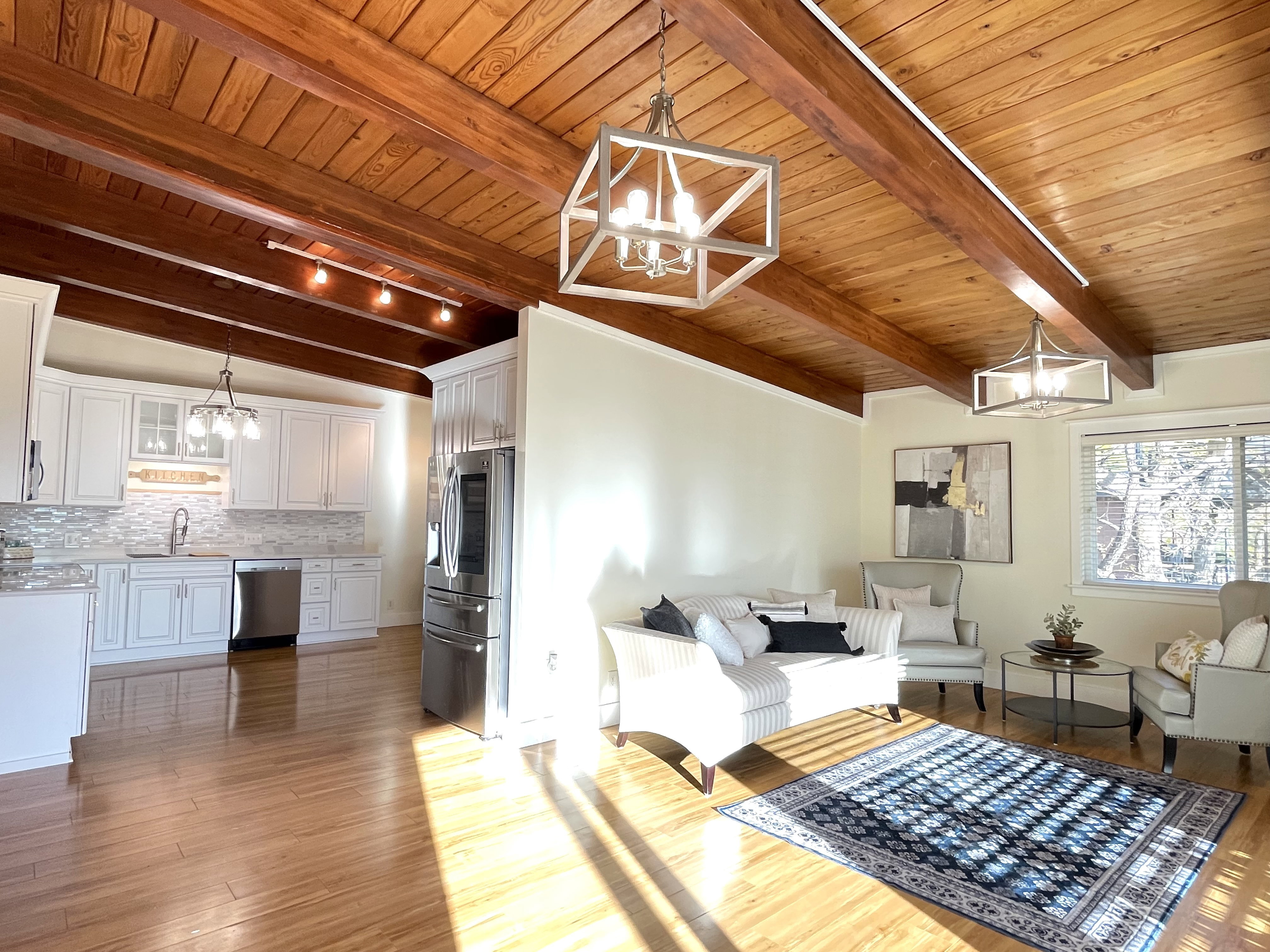 Living area with a chandelier, a wood ceiling with exposed beams, and light wood finished floors
