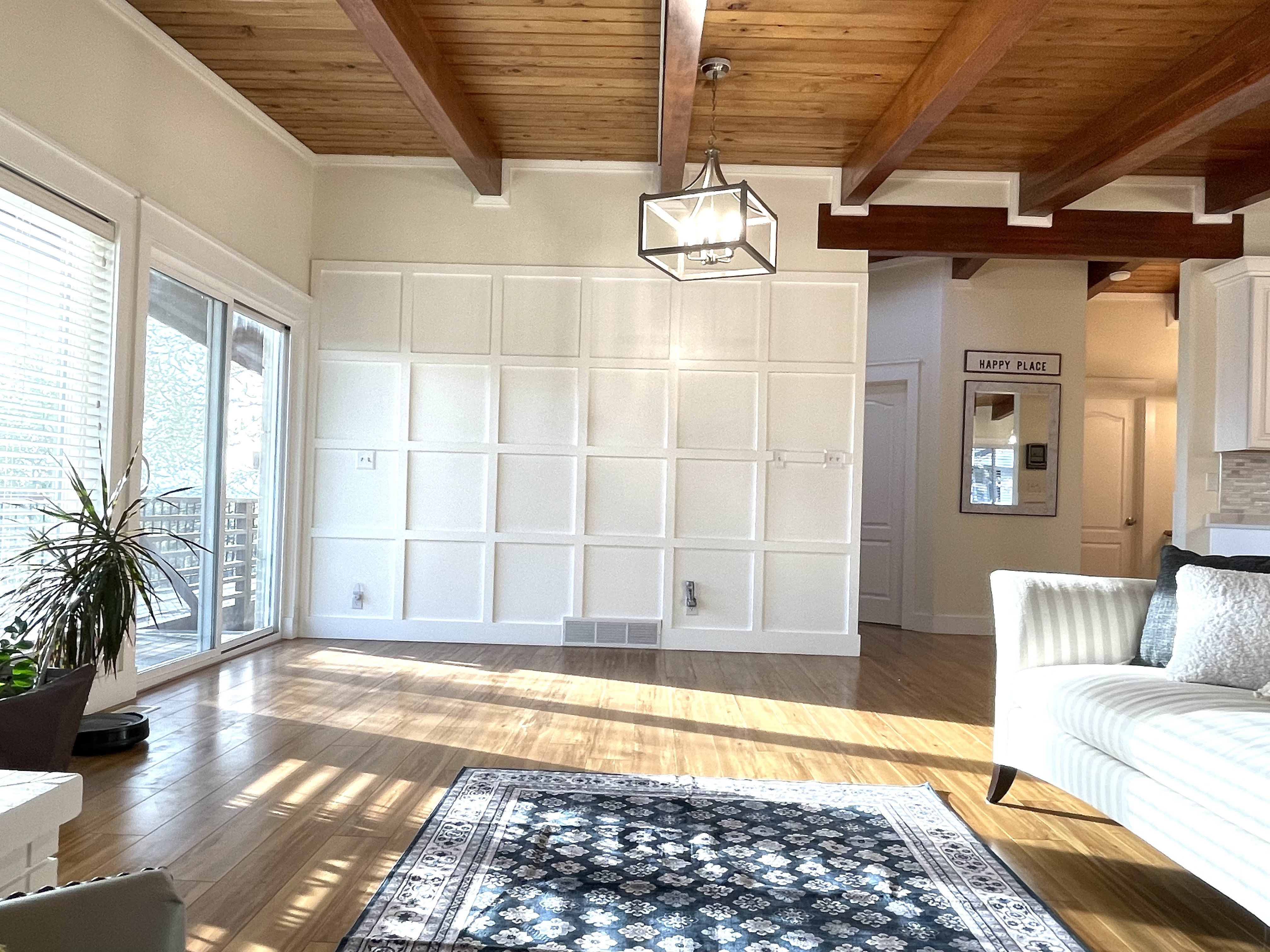Unfurnished room featuring a decorative wall, light wood finished floors, and a wood ceiling with exposed beams