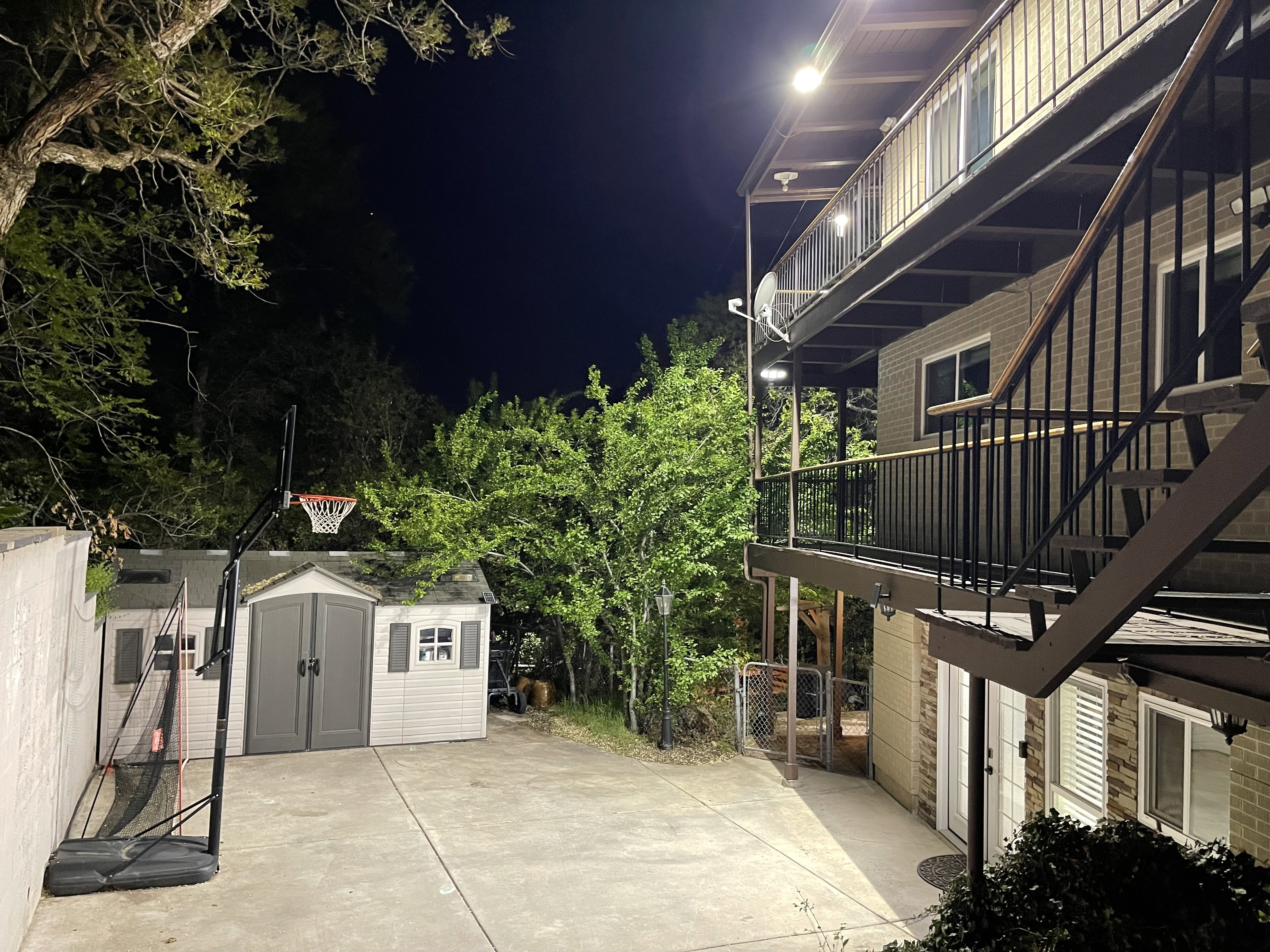 Patio at twilight featuring a shed and a balcony