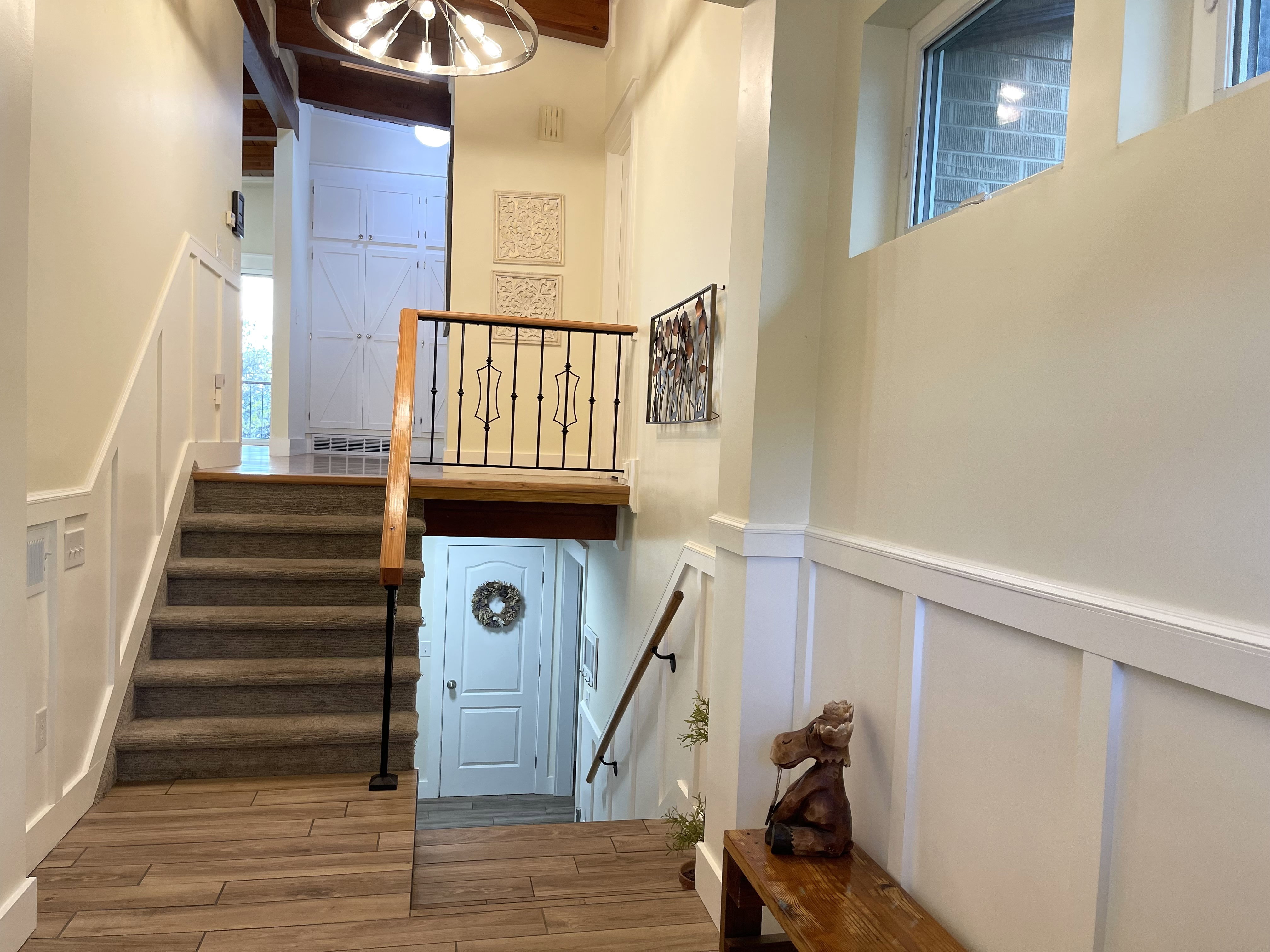 Staircase with a decorative wall, wood finished floors, a wainscoted wall, suspended lighting, and a high ceiling
