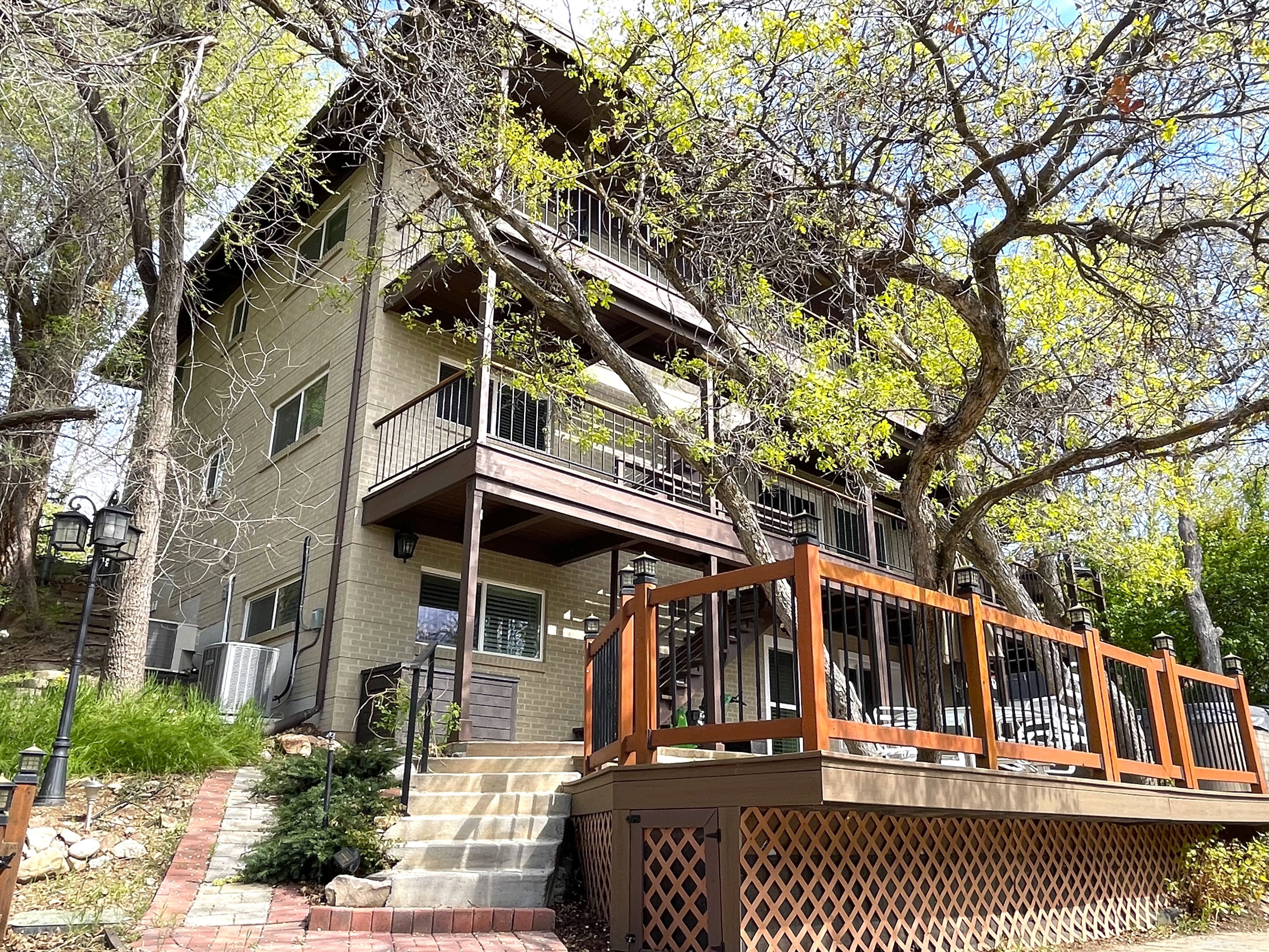 Rear view of property featuring a balcony, brick siding, and a deck