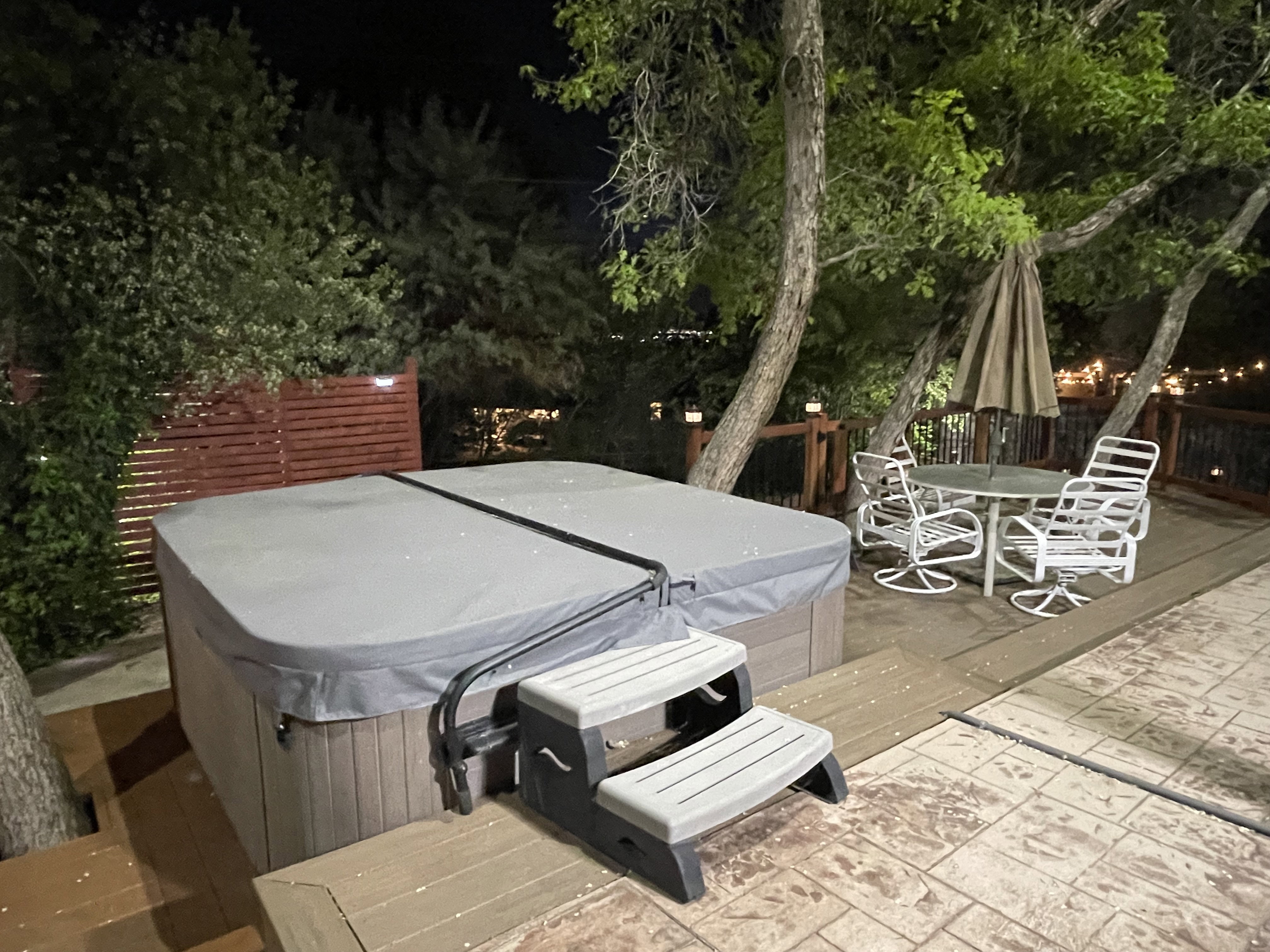 Patio at night featuring a hot tub, outdoor dining space, and a patio area