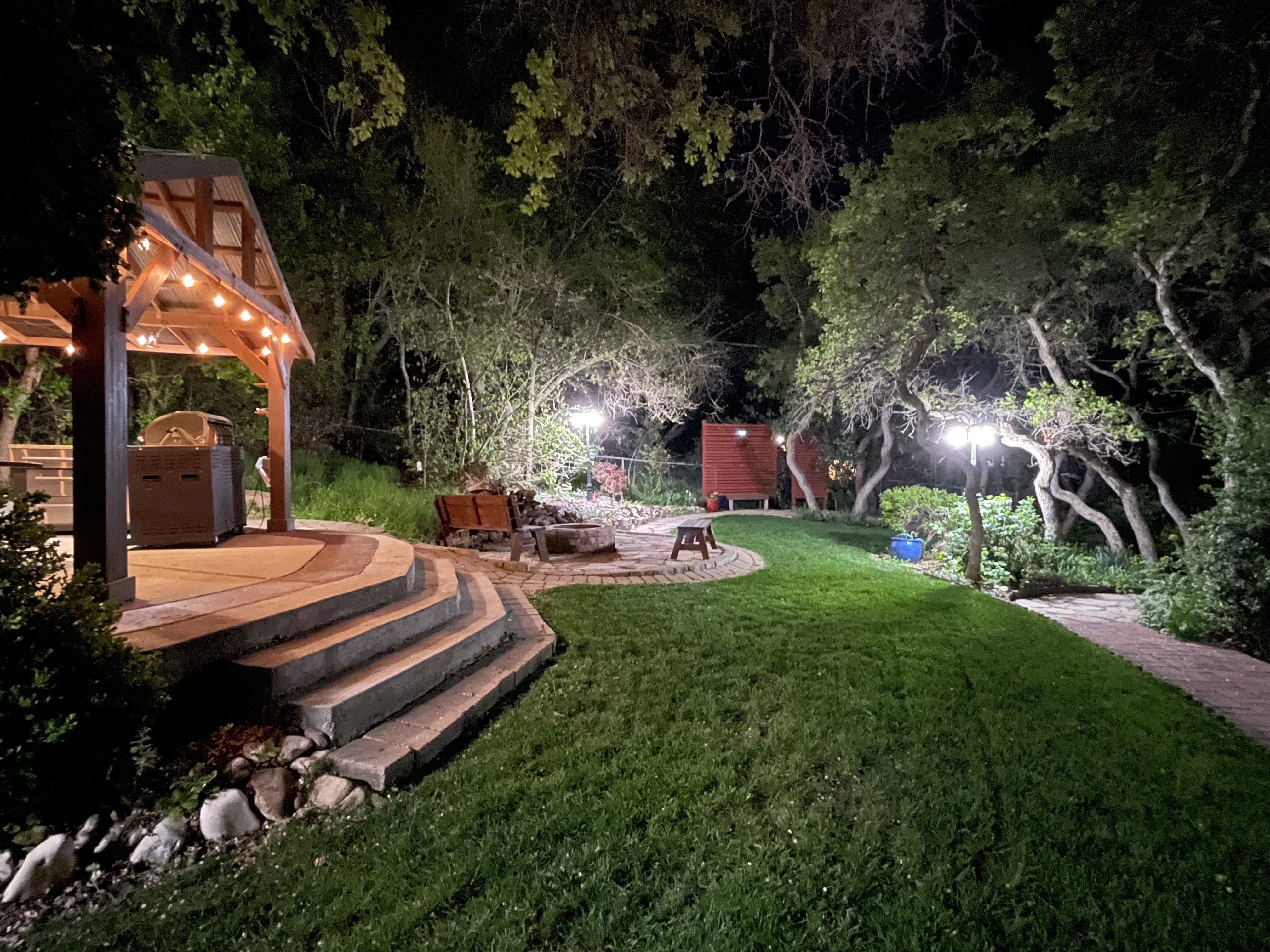 Yard at night featuring a yard, a patio, an outdoor fire pit, and exterior kitchen