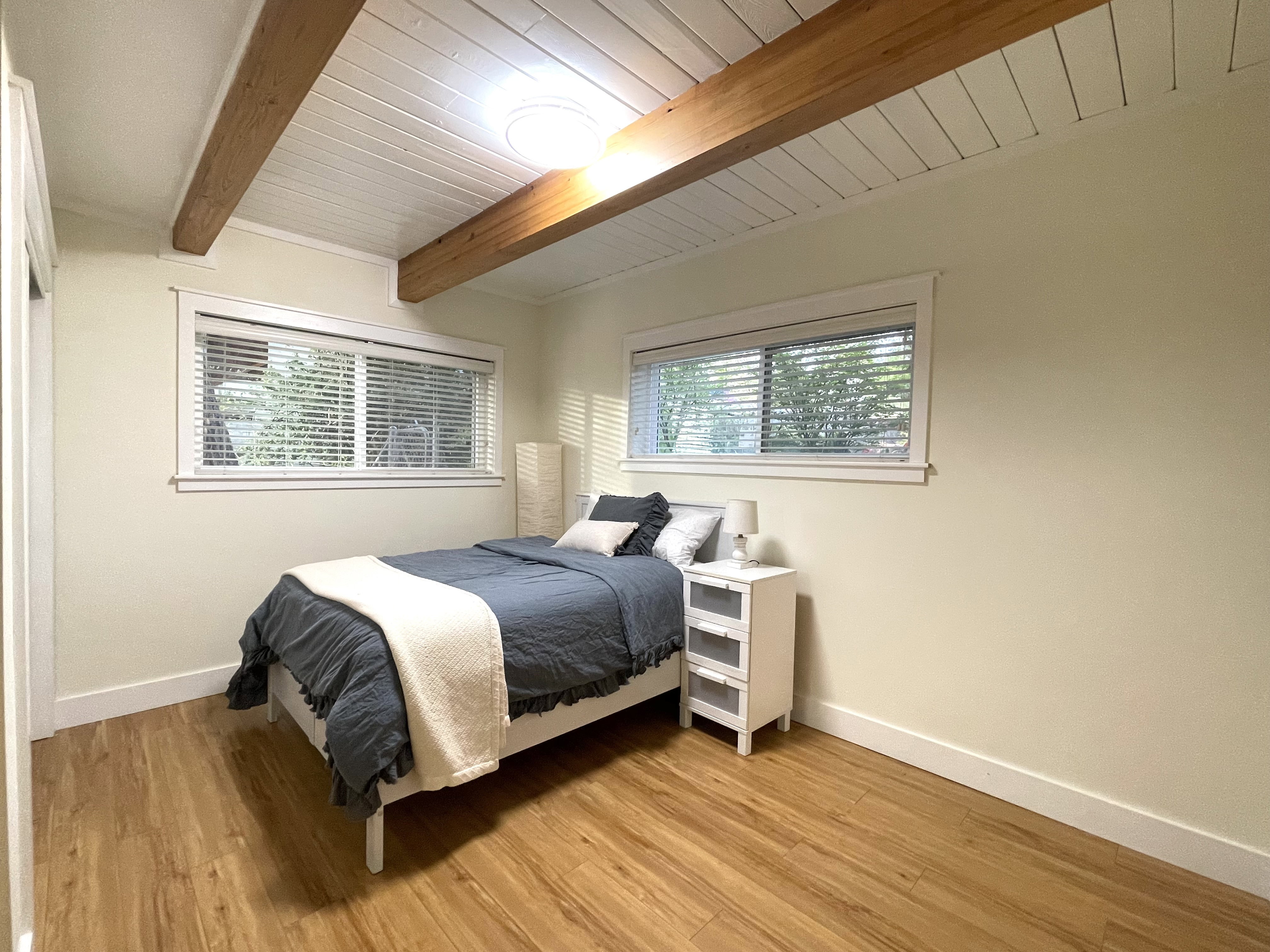 Bedroom with light wood-type flooring and a wooden ceiling with exposed beams