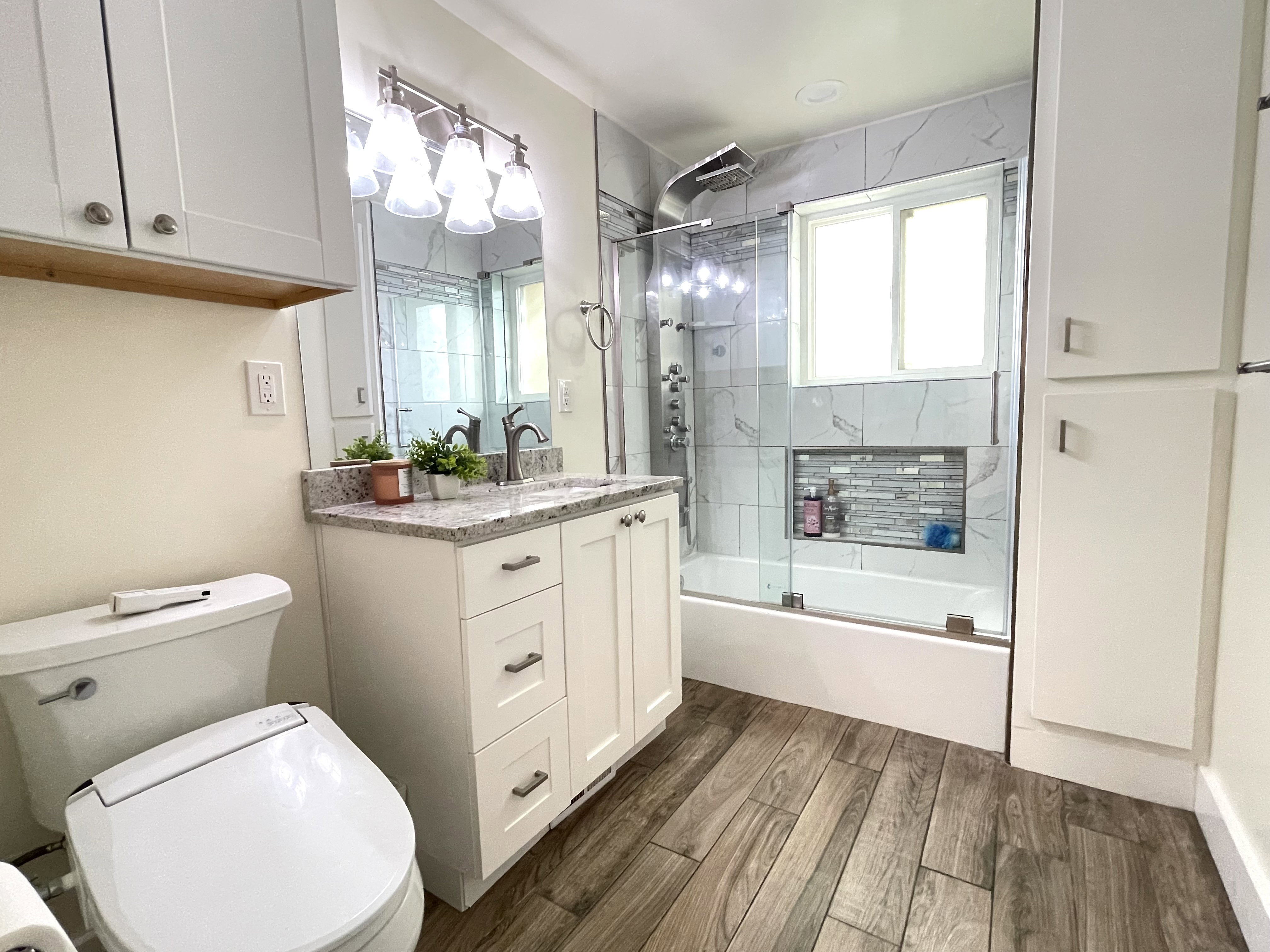 Bathroom with vanity, enclosed tub / shower combo, and dark wood-type flooring