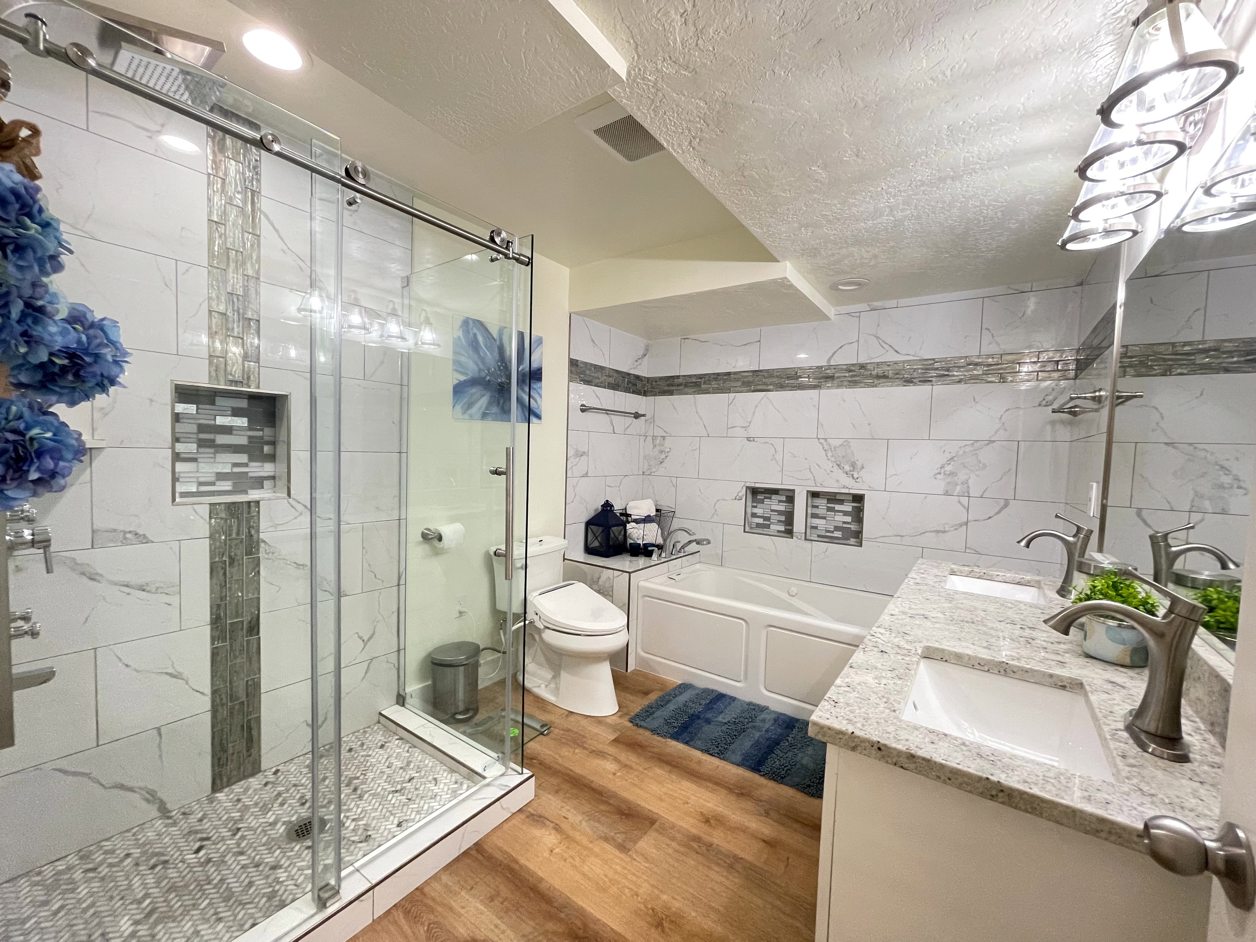 Bathroom with tile walls, double vanity, a textured ceiling, a stall shower, and a garden tub
