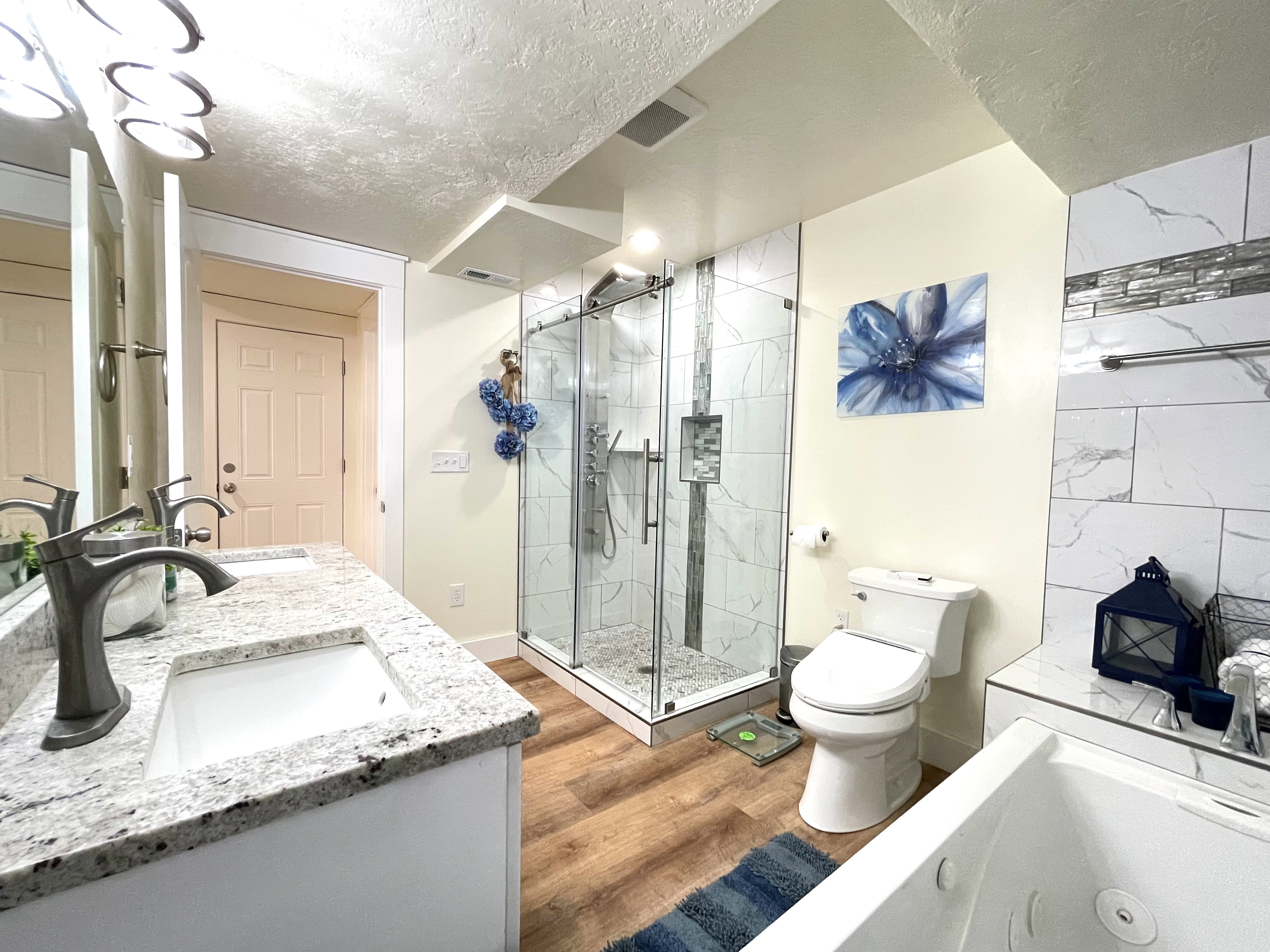 Bathroom featuring a whirlpool tub, double vanity, a textured ceiling, a stall shower, and light wood finished floors