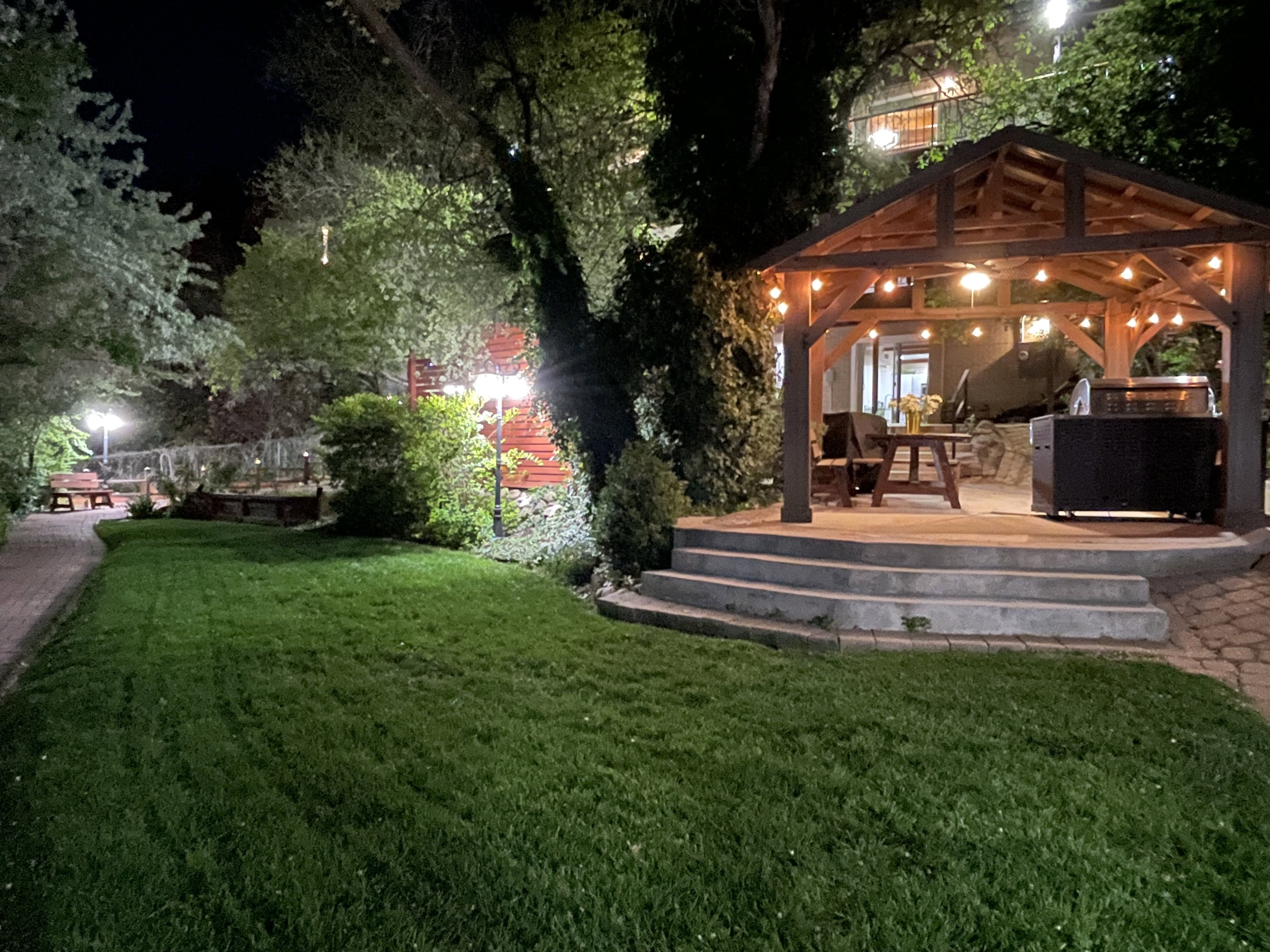 Yard at night featuring a yard, a patio, and an outdoor kitchen