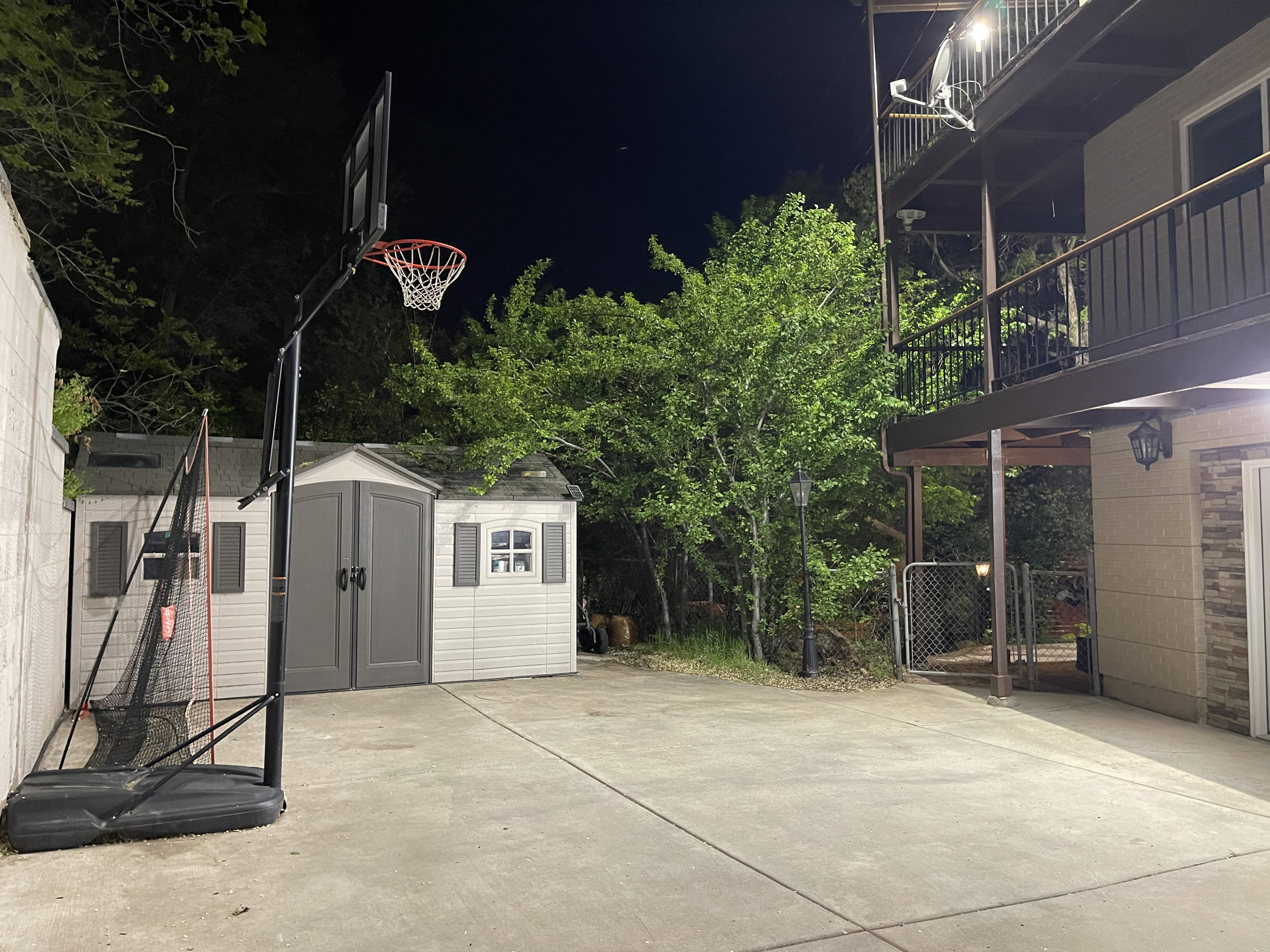 Patio at night with a shed, a balcony, and a patio area
