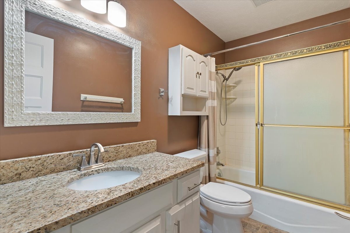 Bathroom with vanity and combined bath / shower with glass door