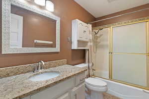 Bathroom with vanity and combined bath / shower with glass door