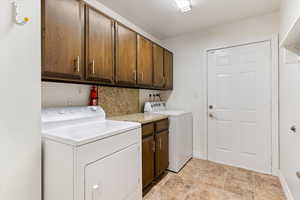 Laundry area with cabinet space, washer and dryer, and stone finish flooring