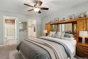 Virtually staged  Bedroom featuring a walk in closet, carpet floors, ceiling fan, and ensuite bath