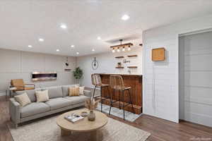 Virtually staged  Living room with dark wood-type flooring, a textured ceiling, recessed lighting, and bar with sink