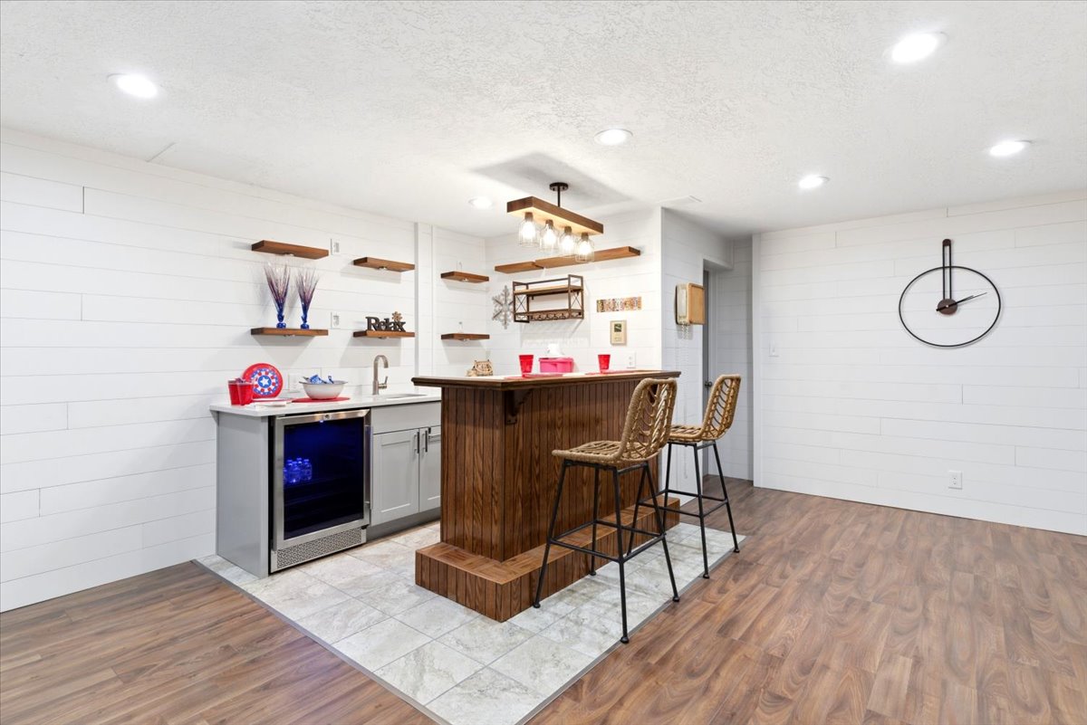 Custom bar area featuring wood-finish flooring, white shiplap walls, recessed lighting, and a built-in beverage cooler