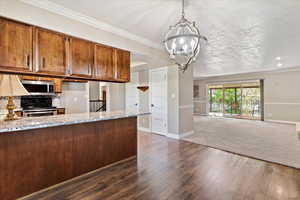 Kitchen featuring stainless steel electric range, dark wood finished floors, a textured ceiling, wood finish cabinets, and ornamental molding