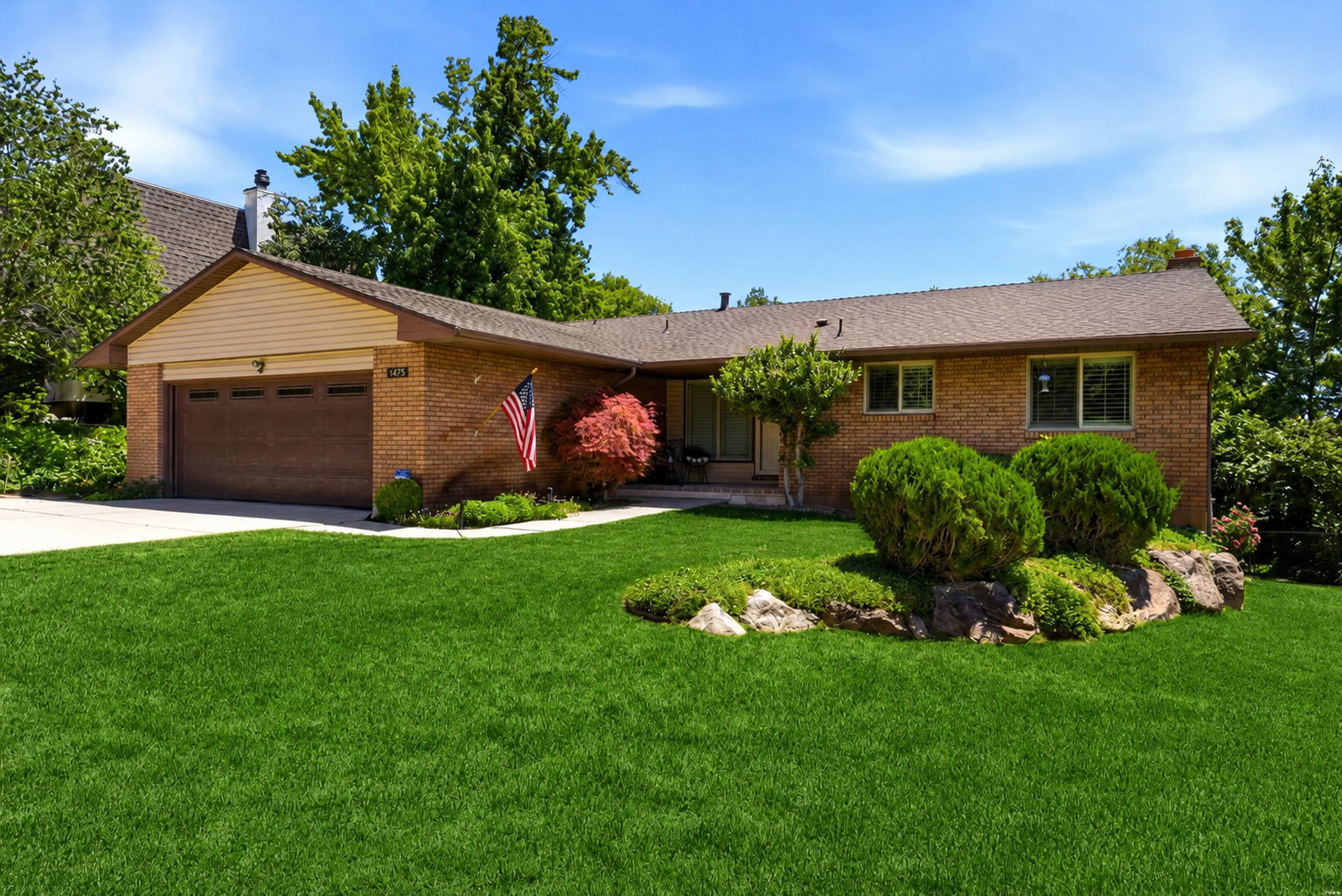 Brick exterior with a brown shingle roof, attached garage with a dark wood-finish door, and a concrete driveway